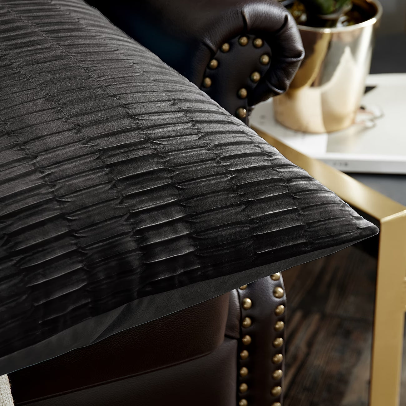 Black textured pillow on a brown leather chair with a blurred background