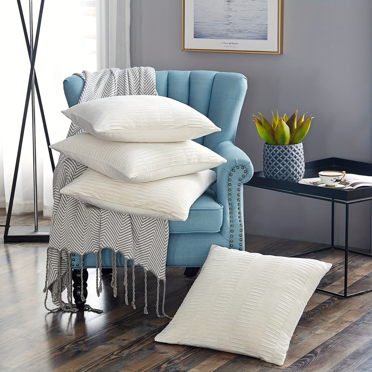 Blue armchair with white pillows and a blanket in a living room setting.