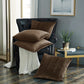 Brown textured pillows on a black leather armchair in a room with a plant and side table.