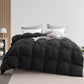 Black quilted comforter on a bed with pillows in a bedroom setting