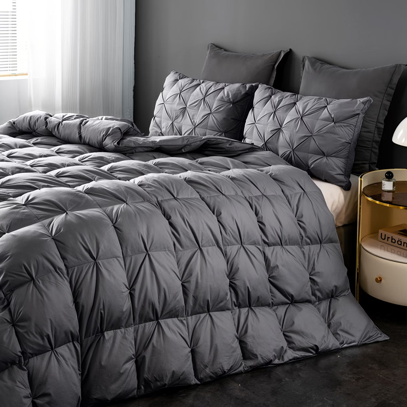 Gray quilted comforter and pillows on a bed in a bedroom setting.
