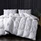 White quilted comforter set on a bed with dark panel walls.