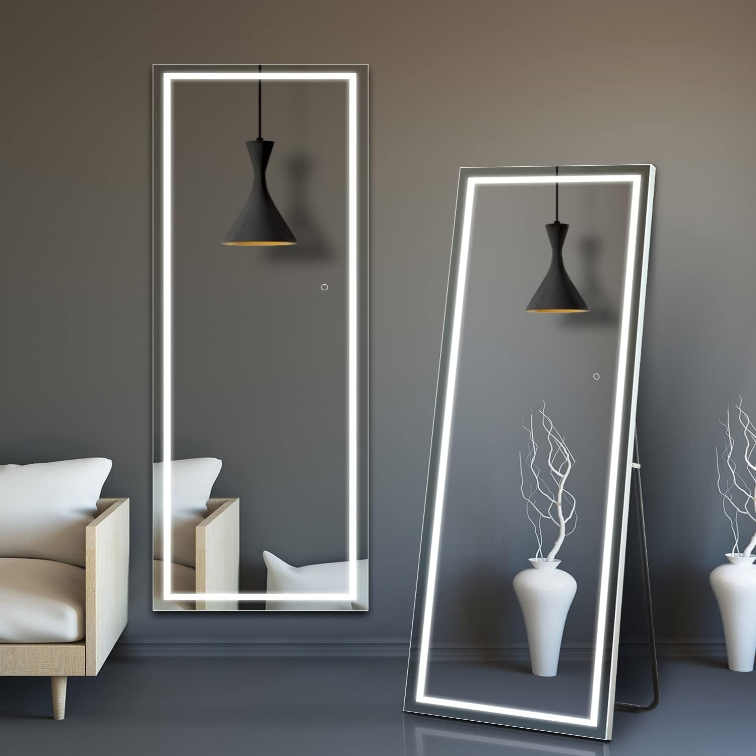 Two illuminated standing mirrors in a room with a sofa and decorative vases.
