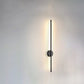 Modern wall light fixture above a round mirror in a bathroom setting.