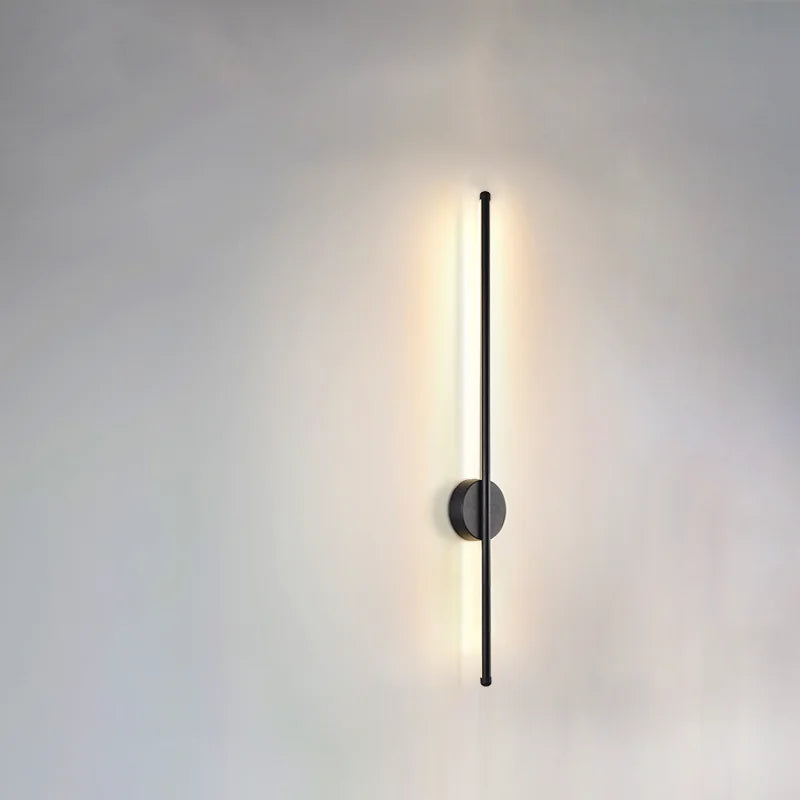 Modern wall light fixture above a round mirror in a bathroom setting.
