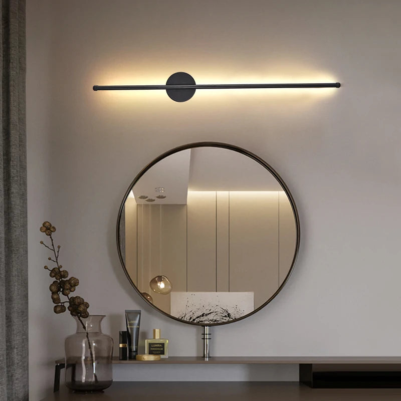Modern wall light fixture above a round mirror in a bathroom setting.