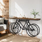 Bicycle-shaped desk with wooden top in a room with a sofa and decorative elements.