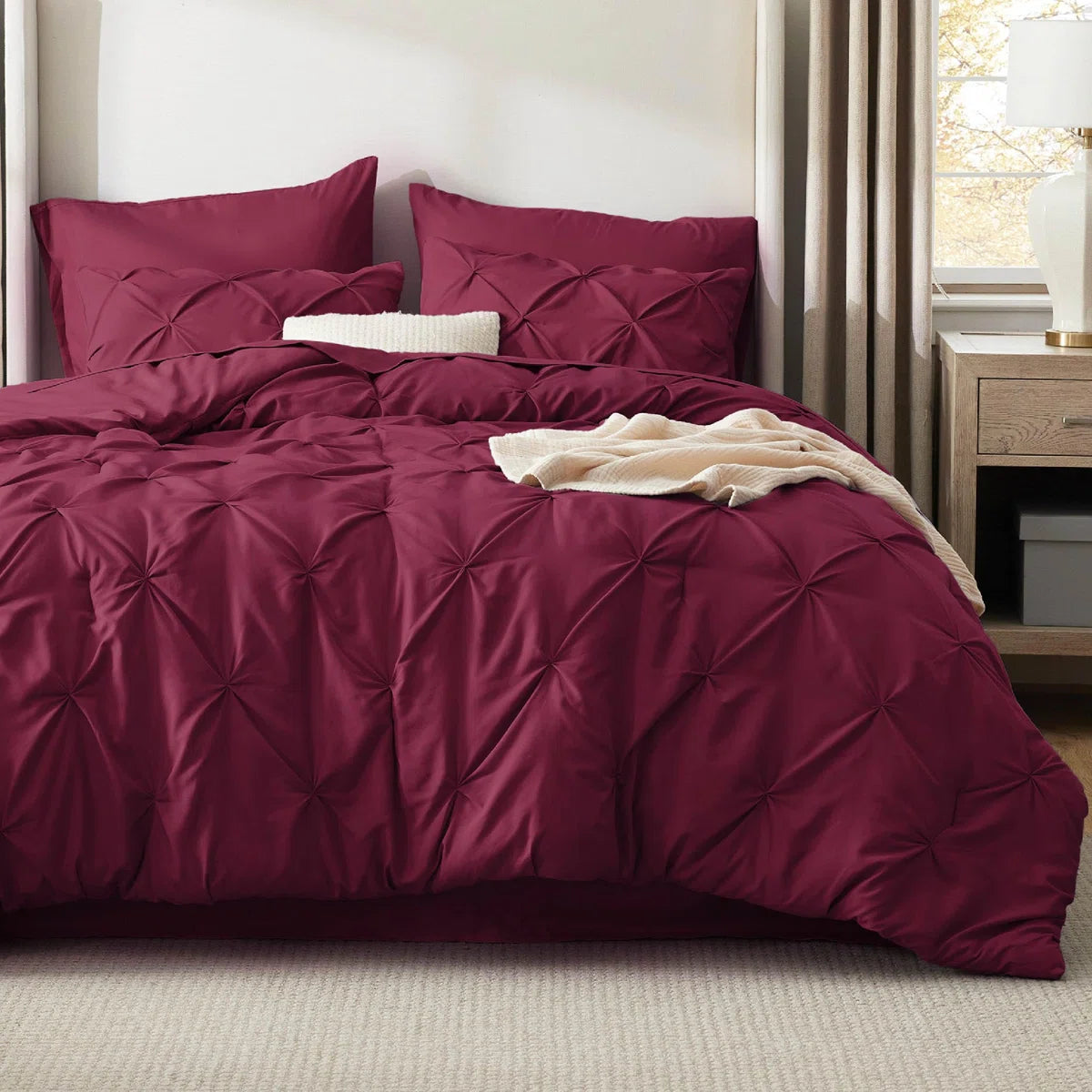 Maroon bedspread with matching pillows on a bed in a bedroom setting.