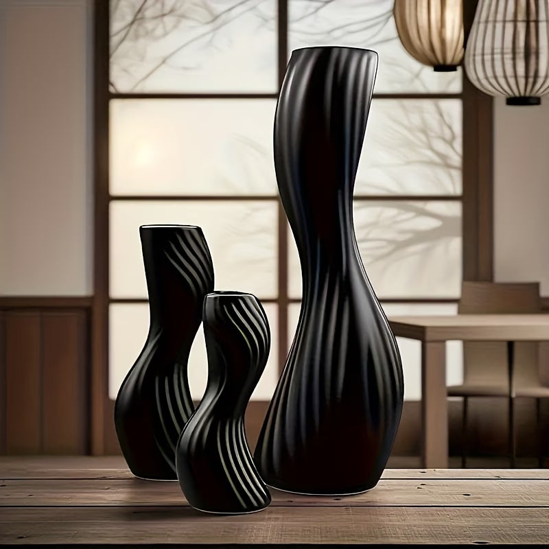 Set of black ceramic vases on a wooden surface with a blurred indoor background