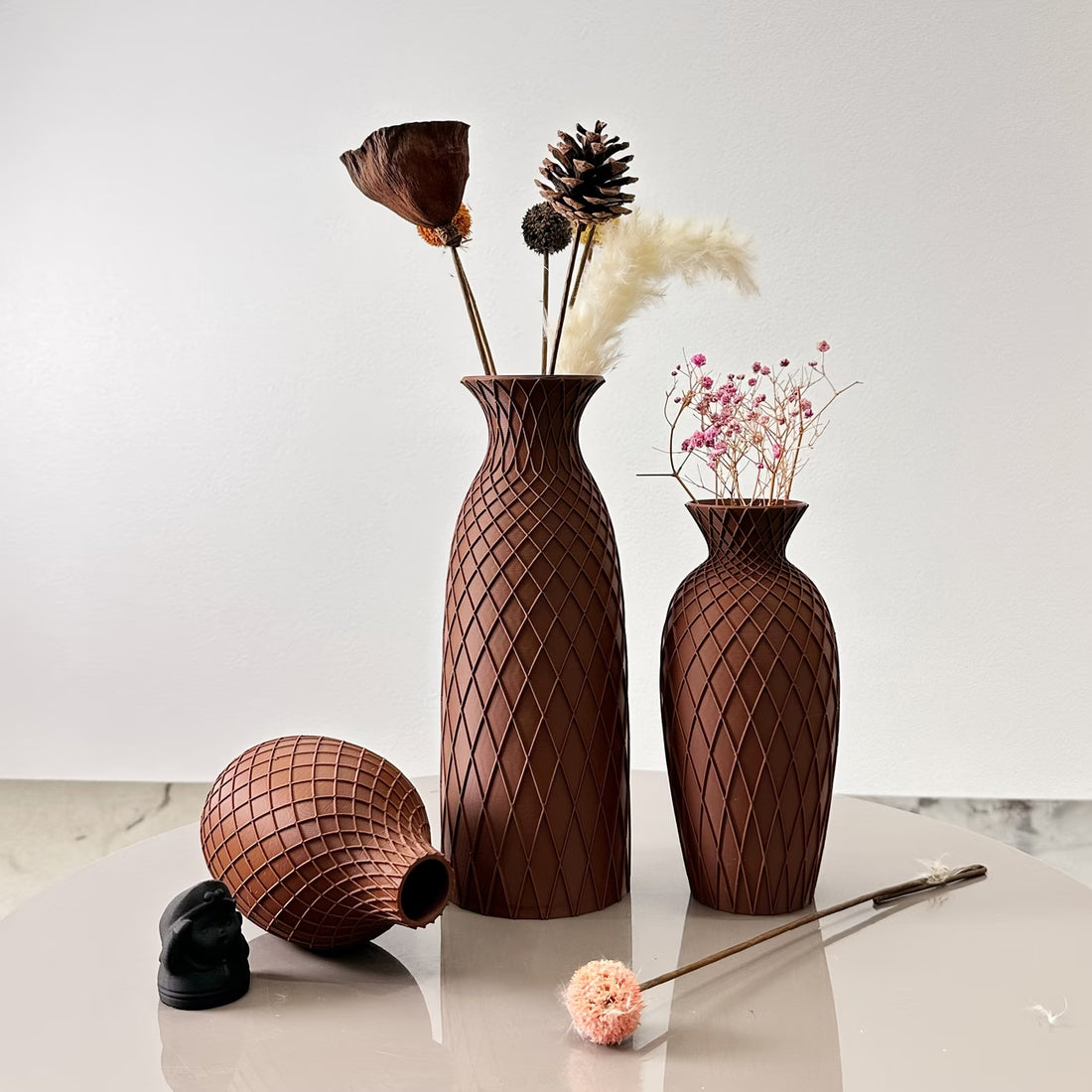 Set of decorative brown vases with textured patterns on a light surface.