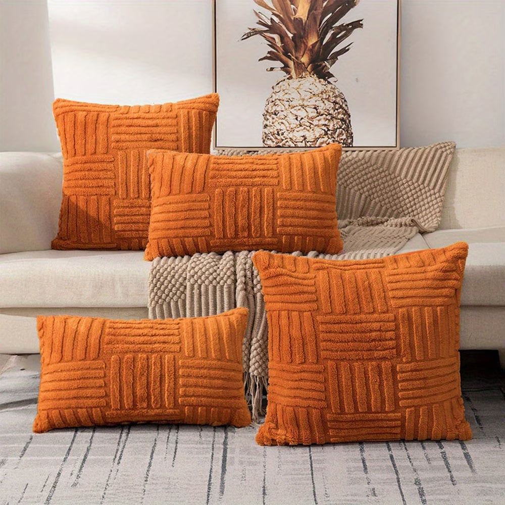 Set of orange textured pillows on a sofa with a pineapple decorative item in the background.