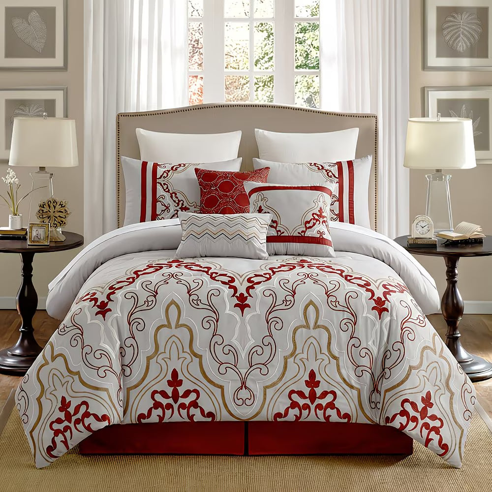 Decorative bedspread with red and gold patterns on a bed in a well-lit bedroom.