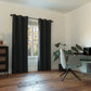Modern room with black curtains, a chair, and a desk.