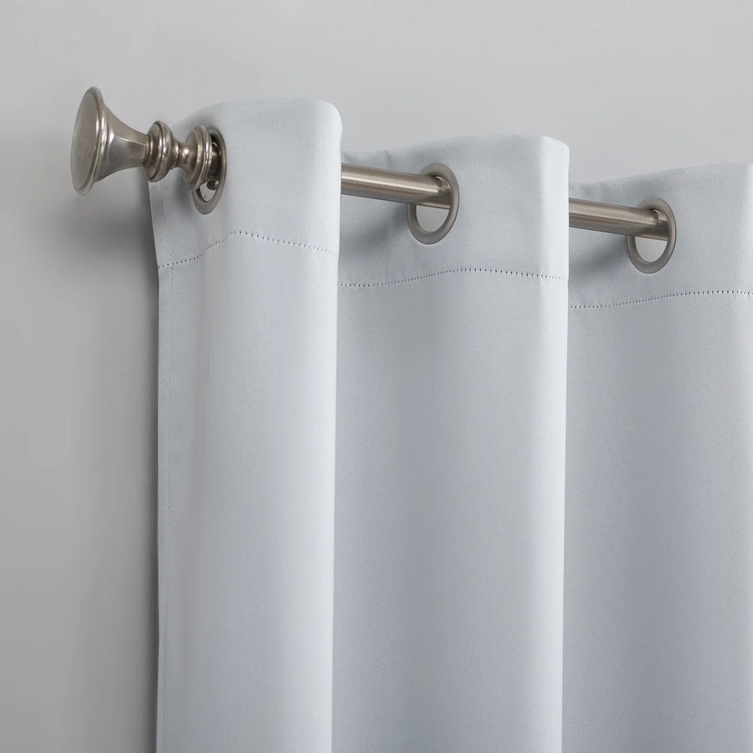 White curtain with silver rings and fixtures on a light gray background
