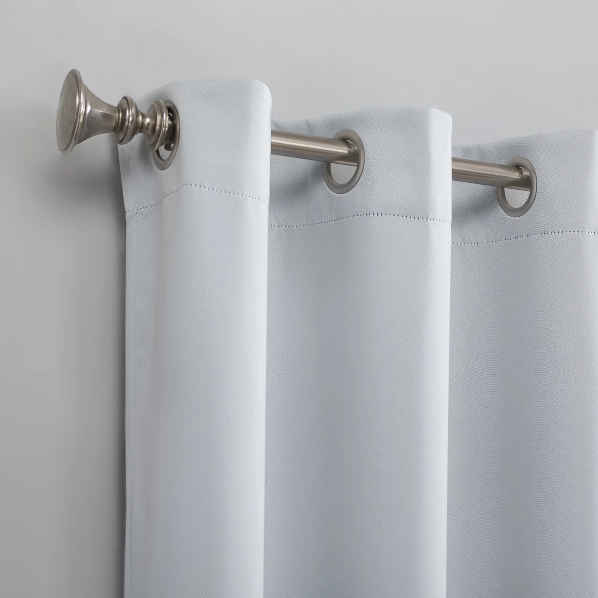White curtain with silver rings and fixtures on a light gray background
