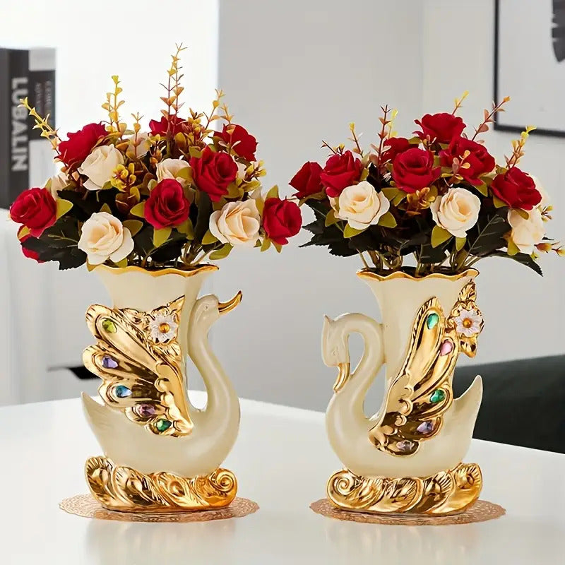 Two decorative swan vases with floral arrangements on a white surface.