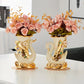 Two decorative swan vases with floral arrangements on a white surface.