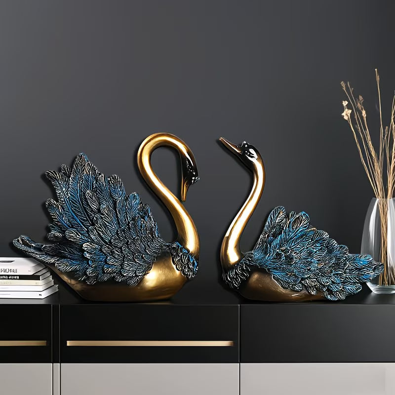 Two decorative swan figures on a dark surface with a plain background