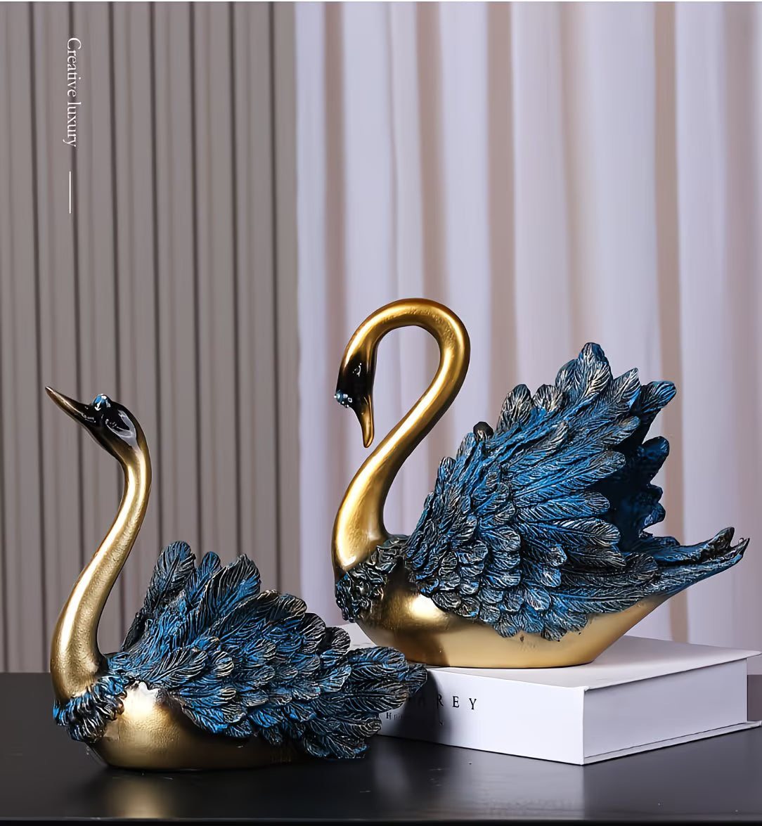 Decorative swan statues with gold and blue feathers on a dark surface.
