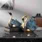 Decorative swan statues on a marble surface with a neutral background