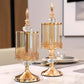 Two ornate gold candle holders on a table with a blurred background