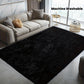 Black rug in front of a gray sofa with 'Machine Washable' text above.