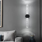 Modern wall sconce on a gray wall with a sofa and decorative items in the foreground