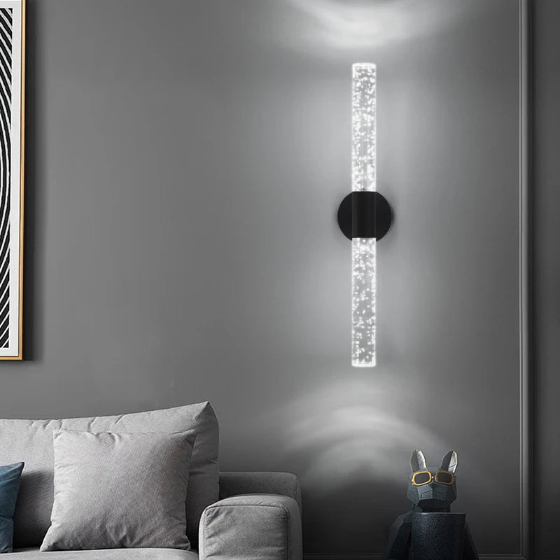 Modern wall sconce on a gray wall with a sofa and decorative items in the foreground