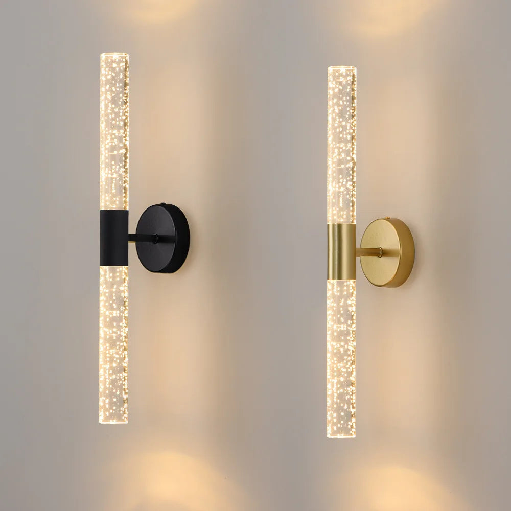 Two modern wall sconces, one black and one gold, on a neutral wall.