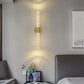 Modern wall sconce in a bedroom setting with a bed and decor items.