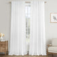 White sheer curtains hanging in front of a window with a side table and chair in the background.