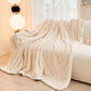 Beige textured blanket draped over a sofa in a living room setting.