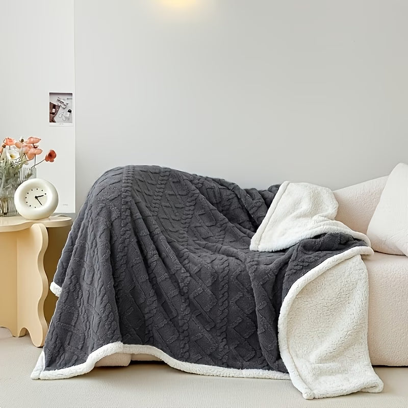 Gray quilted blanket draped over a sofa in a living room setting.