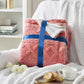 Pink blanket with a blue ribbon on a white surface, surrounded by books and a cup of tea.