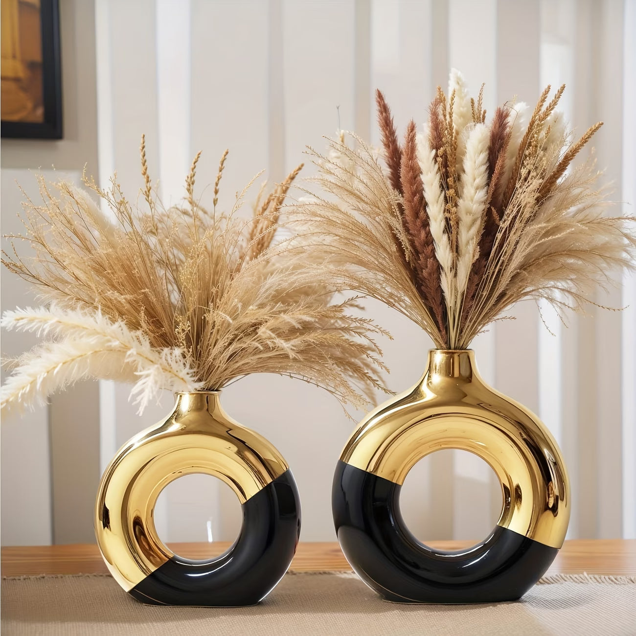 Two decorative vases with gold and black design on a table.