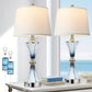 Two table lamps with USB ports on a surface with electronic devices and books.