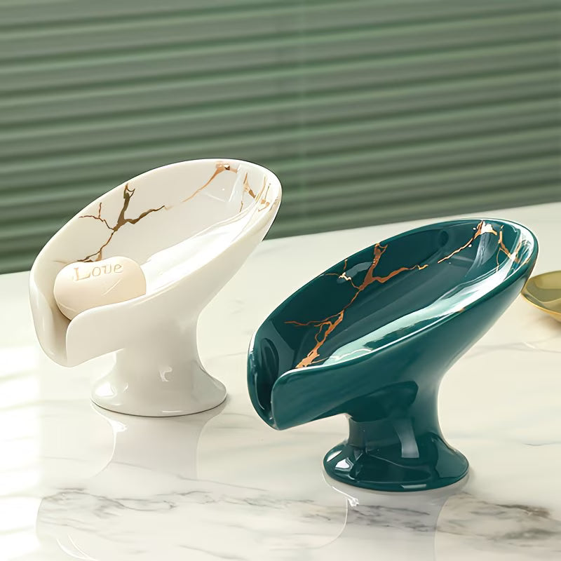 Two decorative bowls, one white with gold accents and one teal with gold accents, on a marble surface.