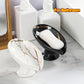 Two marble-patterned soap dishes with a bar of soap on a bathroom counter.