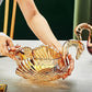 Gold swan-shaped bowl held by a person on a reflective surface