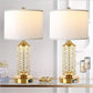 Two table lamps with gold bases and diamond-patterned glass shades on a glass surface.