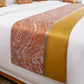 Marble-patterned bed runner with gold accent on a bed