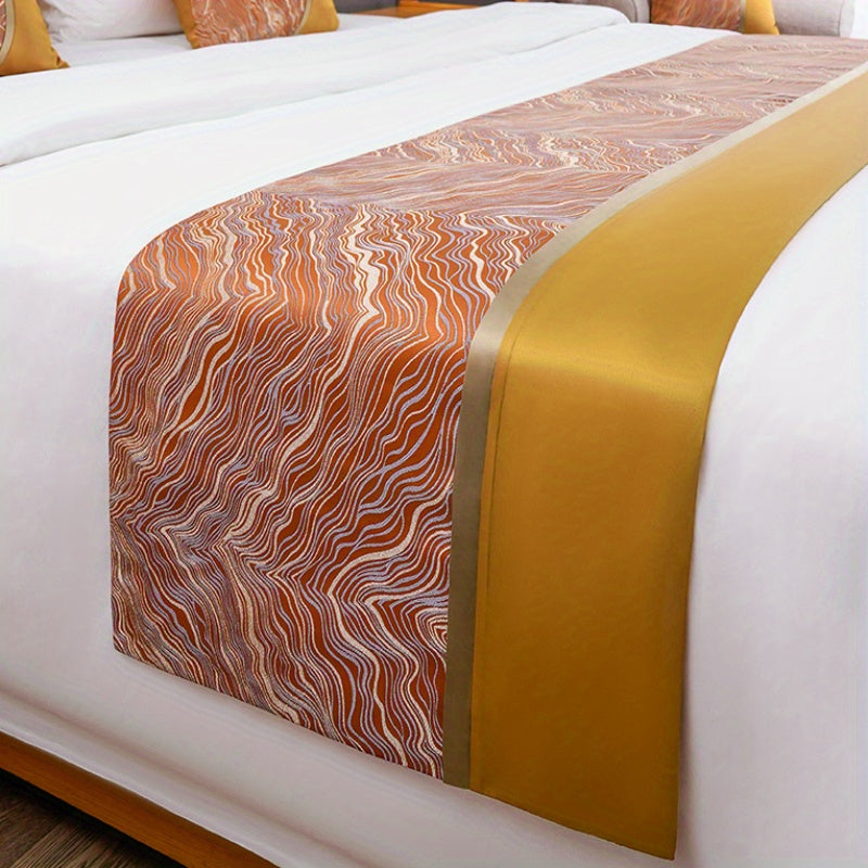 Marble-patterned bed runner with gold accent on a bed