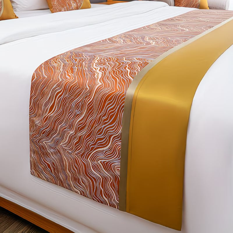Marble-patterned bed runner with gold accent on a bed