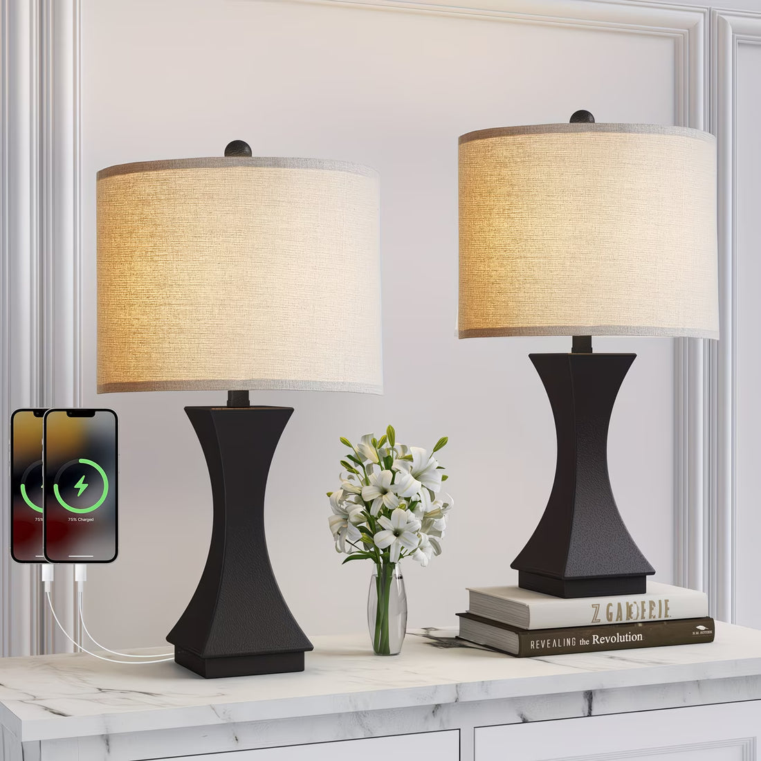 Two black table lamps with beige lampshades on a white surface, with a smartphone displaying charging symbols.