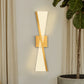 Modern wall sconces on a neutral wall with a plant in the corner