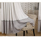 Gray and white curtain draped over a chair in a room with a patterned wall.