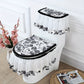 Toilet set with floral design and black trim on a white toilet against a decorative wall.
