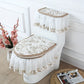Decorative toilet seat cover set with floral patterns on a white toilet against a white wall.