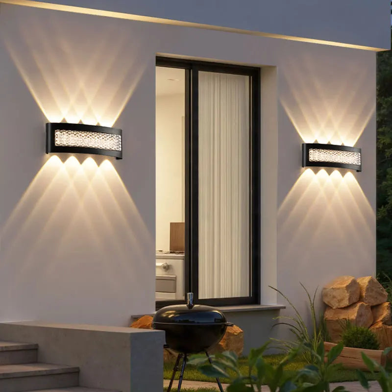 Modern outdoor setting with wall lights, a grill, and plants.