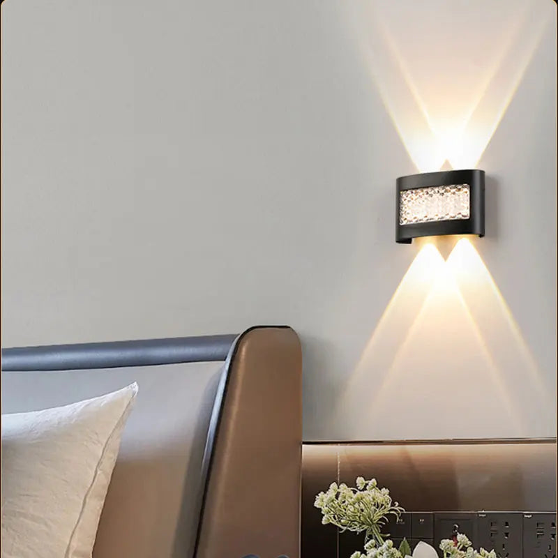 Modern wall-mounted light fixture on a neutral wall above a bed.